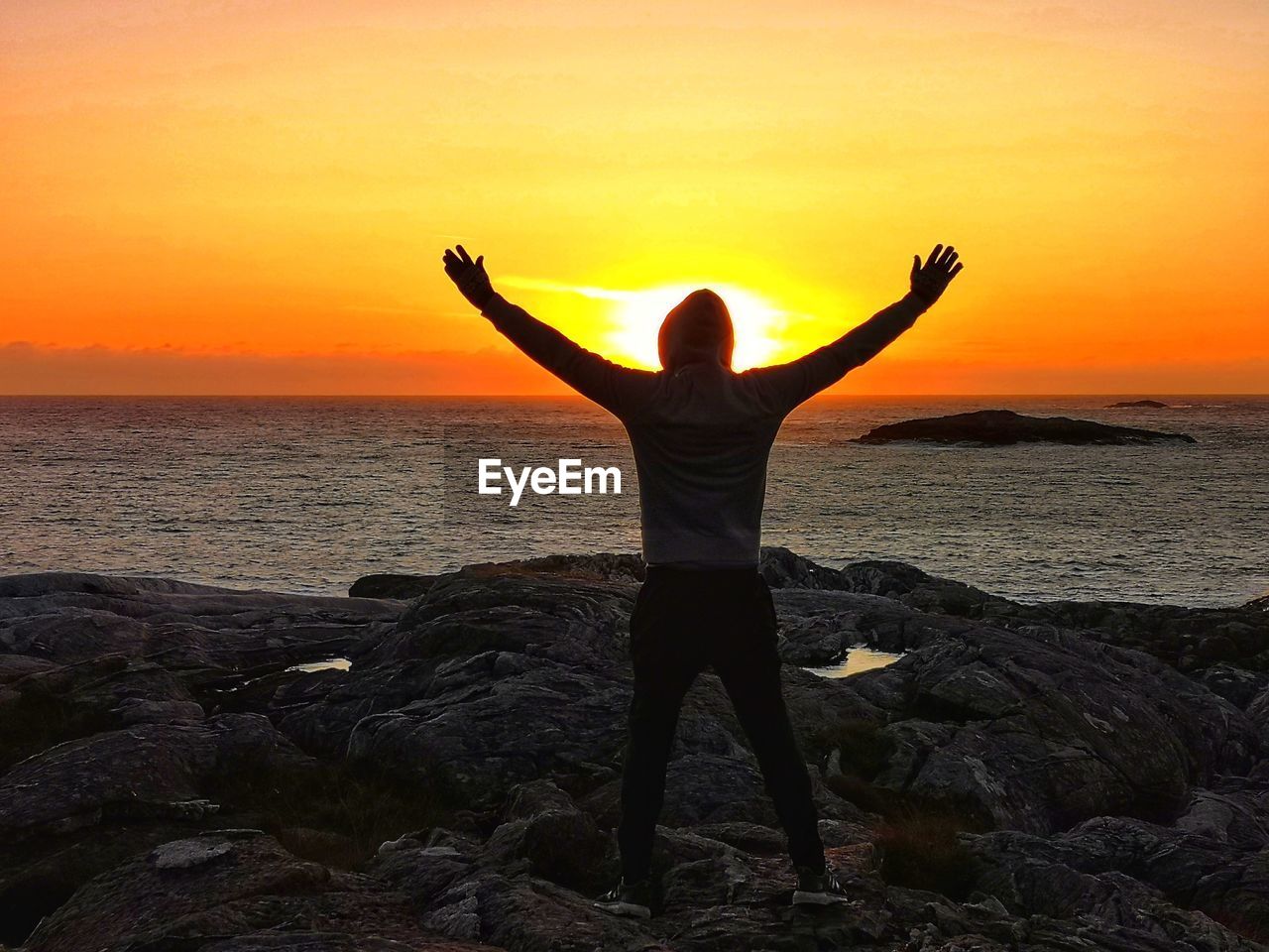 FULL LENGTH OF MAN STANDING ON ROCK AT BEACH AGAINST SKY