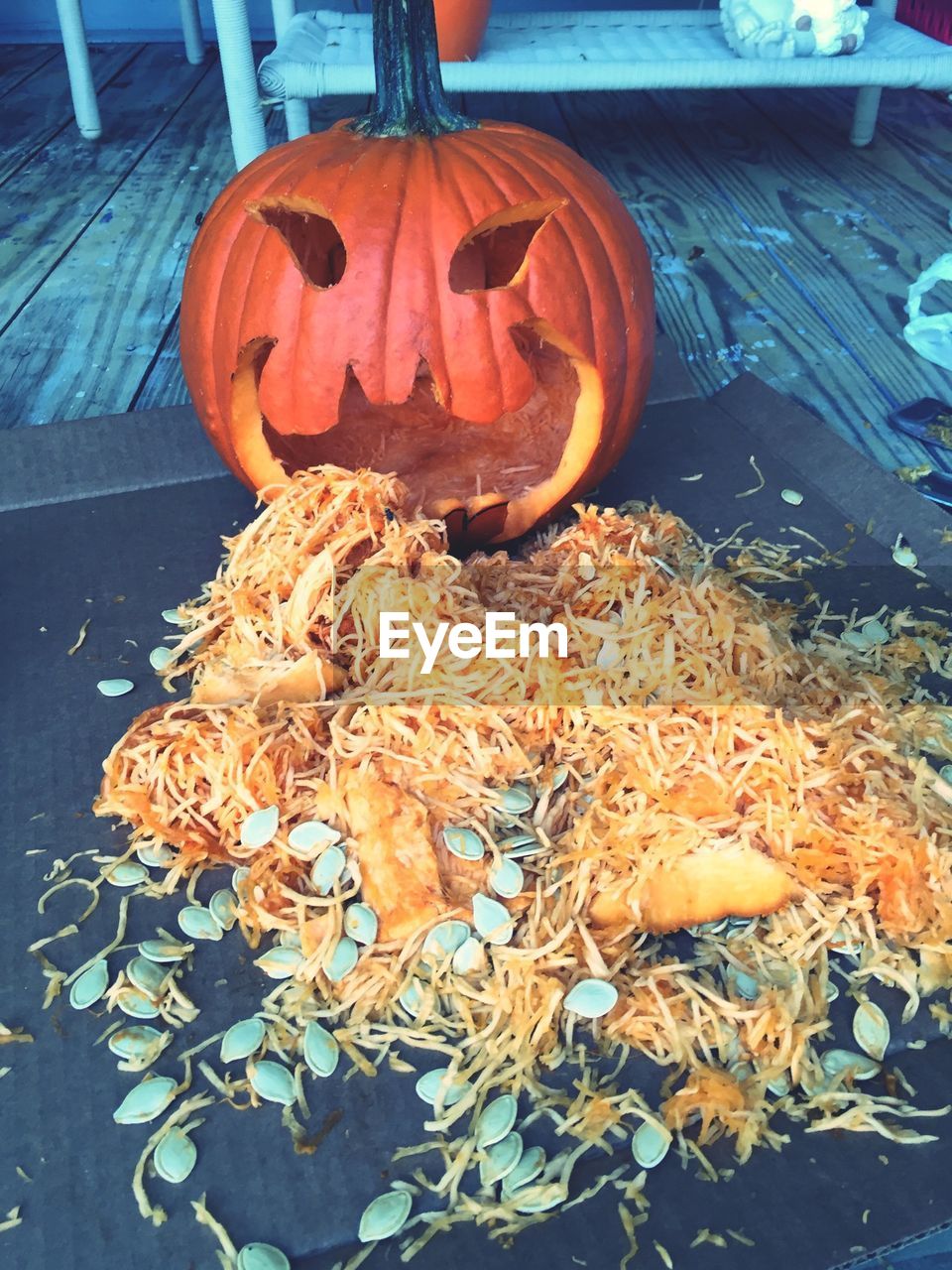 Anthropomorphic pumpkin face with messy food and seed on porch