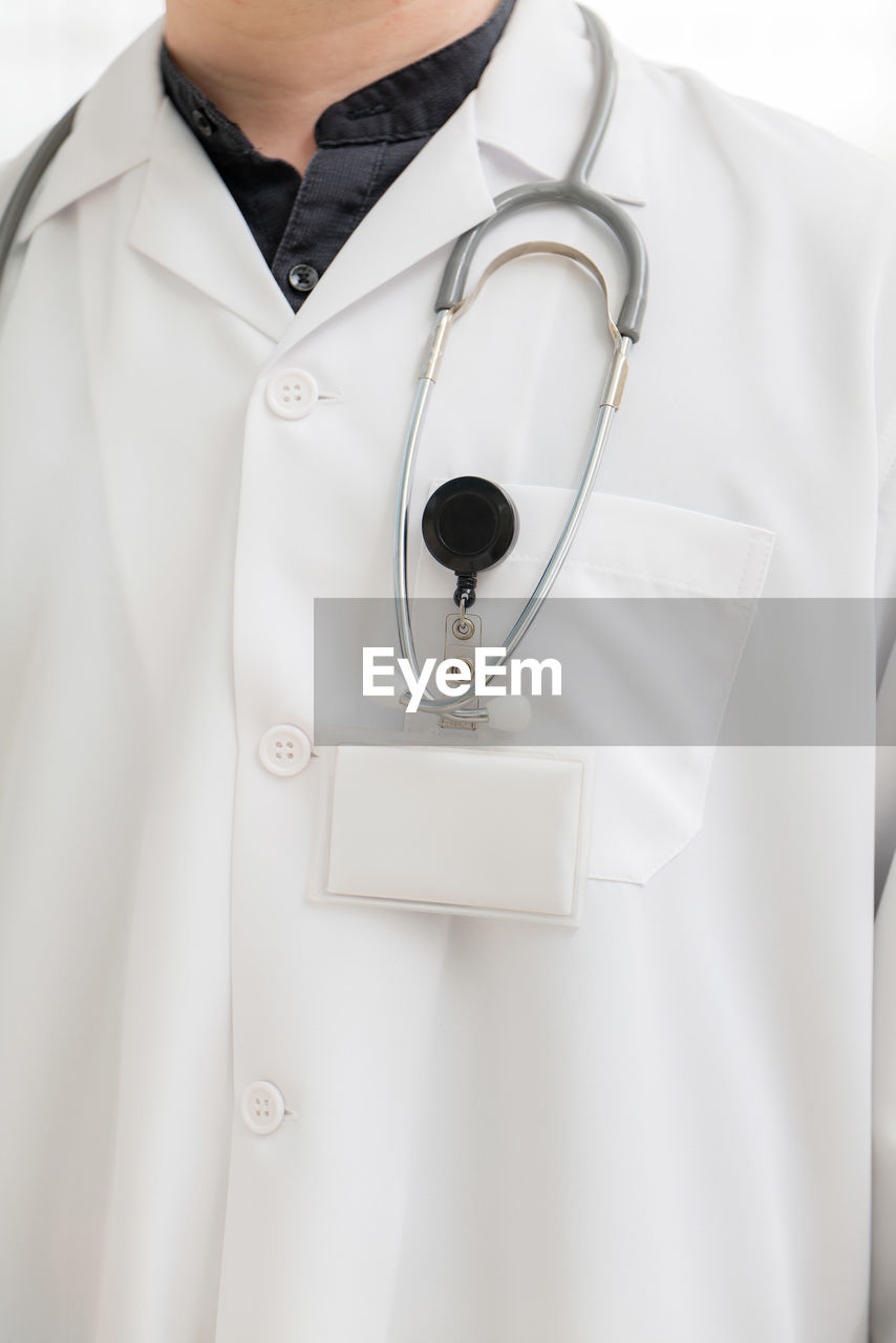 midsection of doctor holding stethoscope against white background