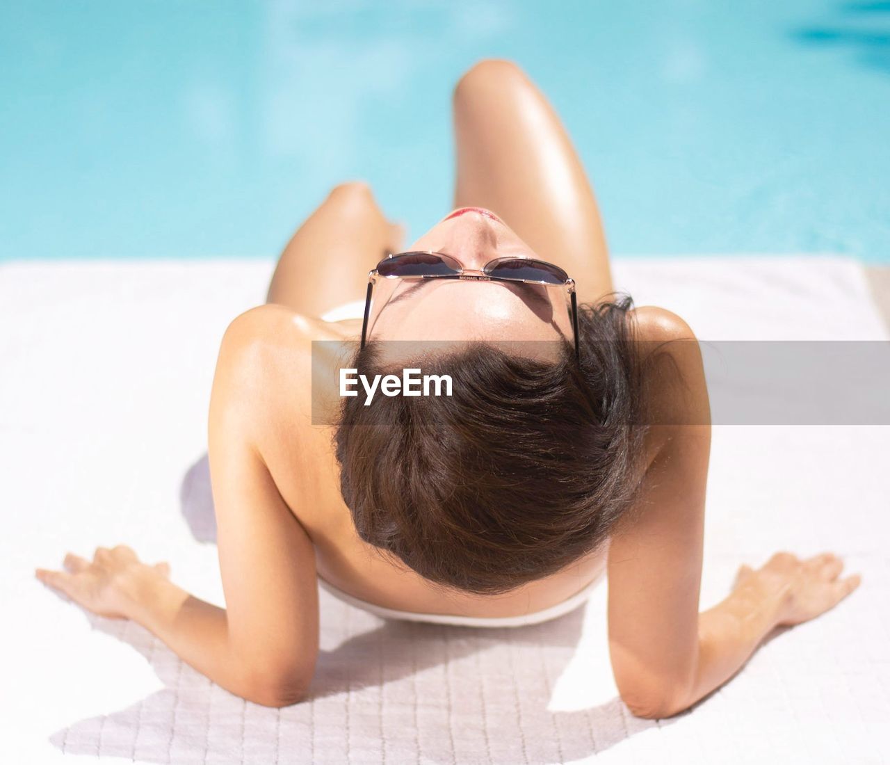 MIDSECTION OF WOMAN LYING ON SWIMMING POOL