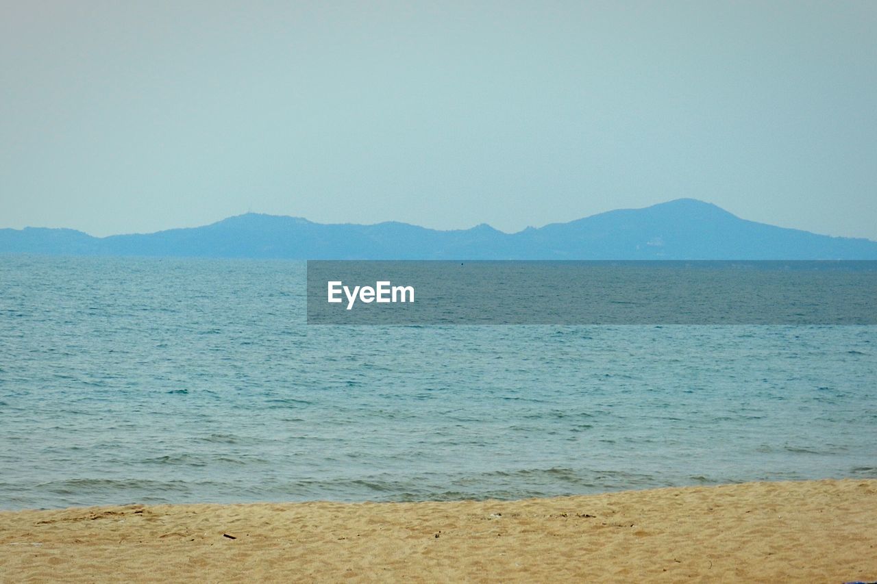 SCENIC VIEW OF SEA AND MOUNTAINS AGAINST CLEAR SKY