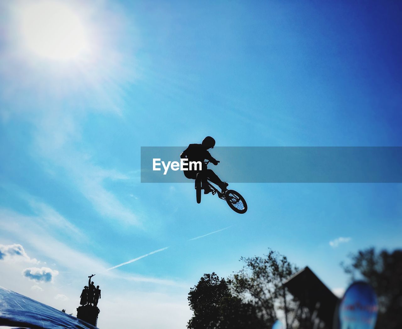 LOW ANGLE VIEW OF MAN JUMPING ON WHEEL