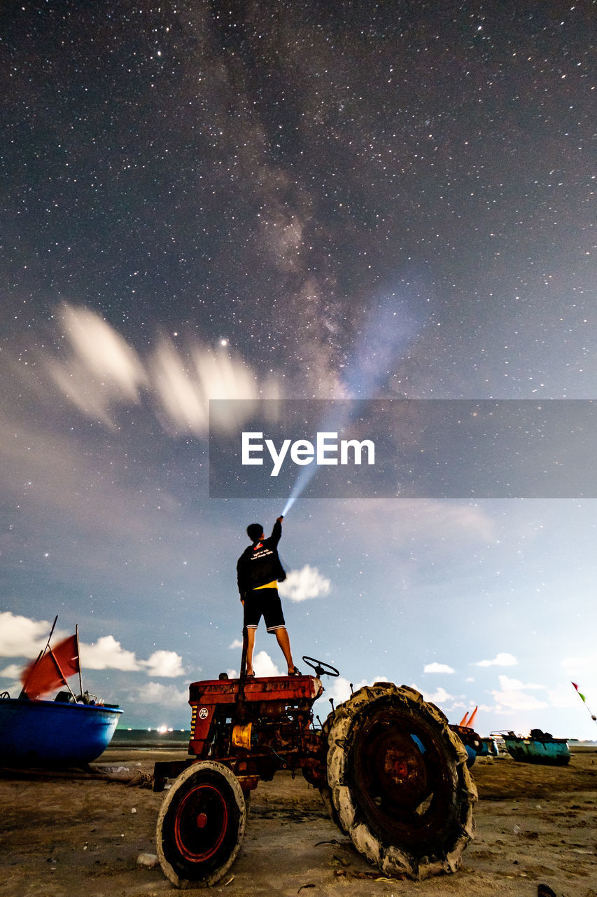 Man standing on field against sky at night