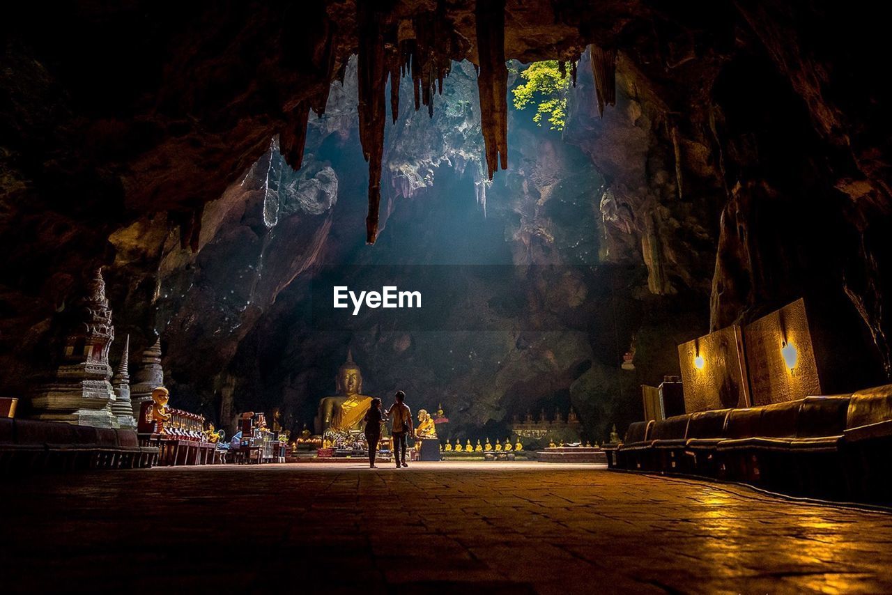 People walking in temple under cave