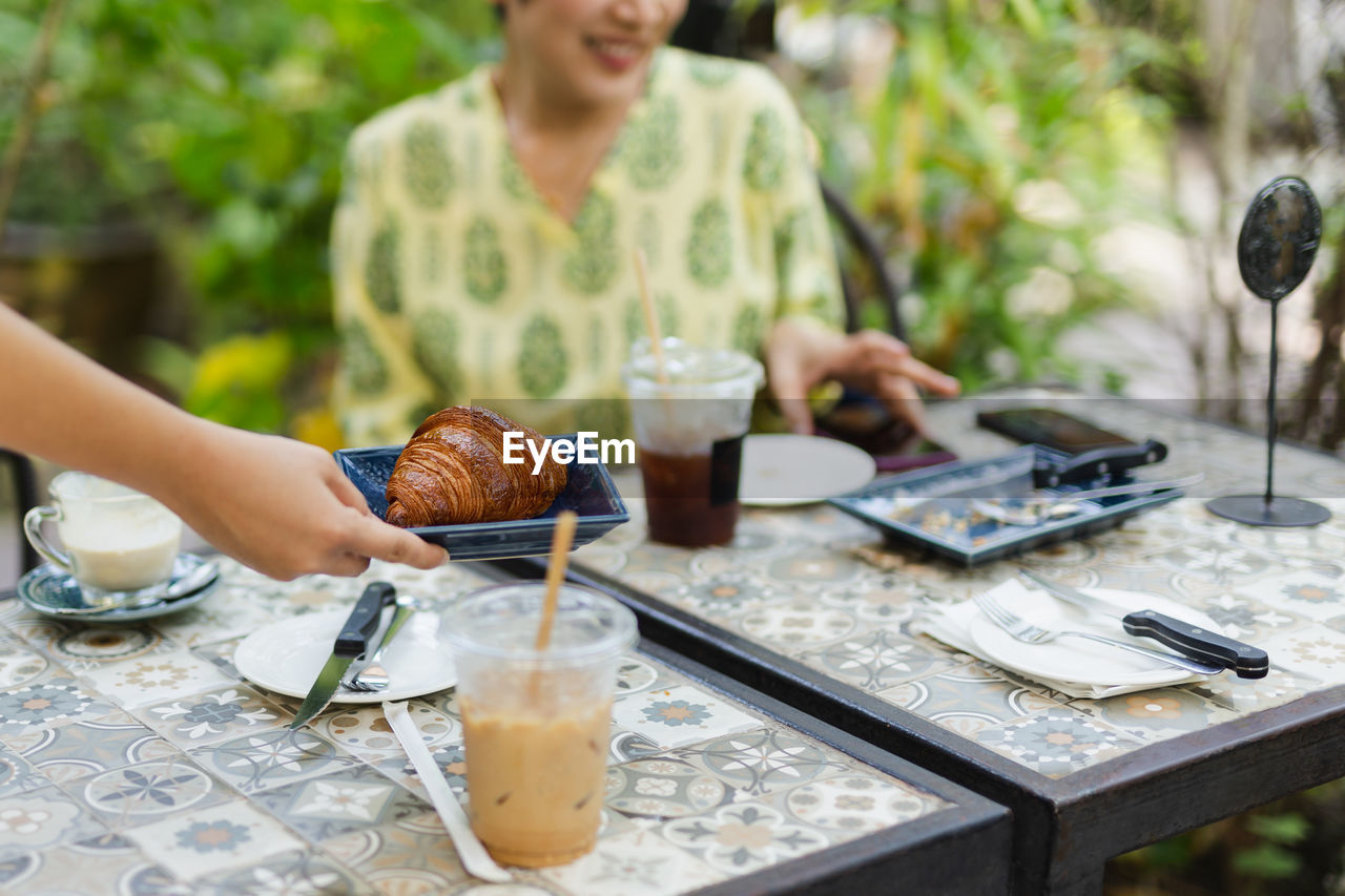 Waitress serving croissants in the coffee shop outdoor.