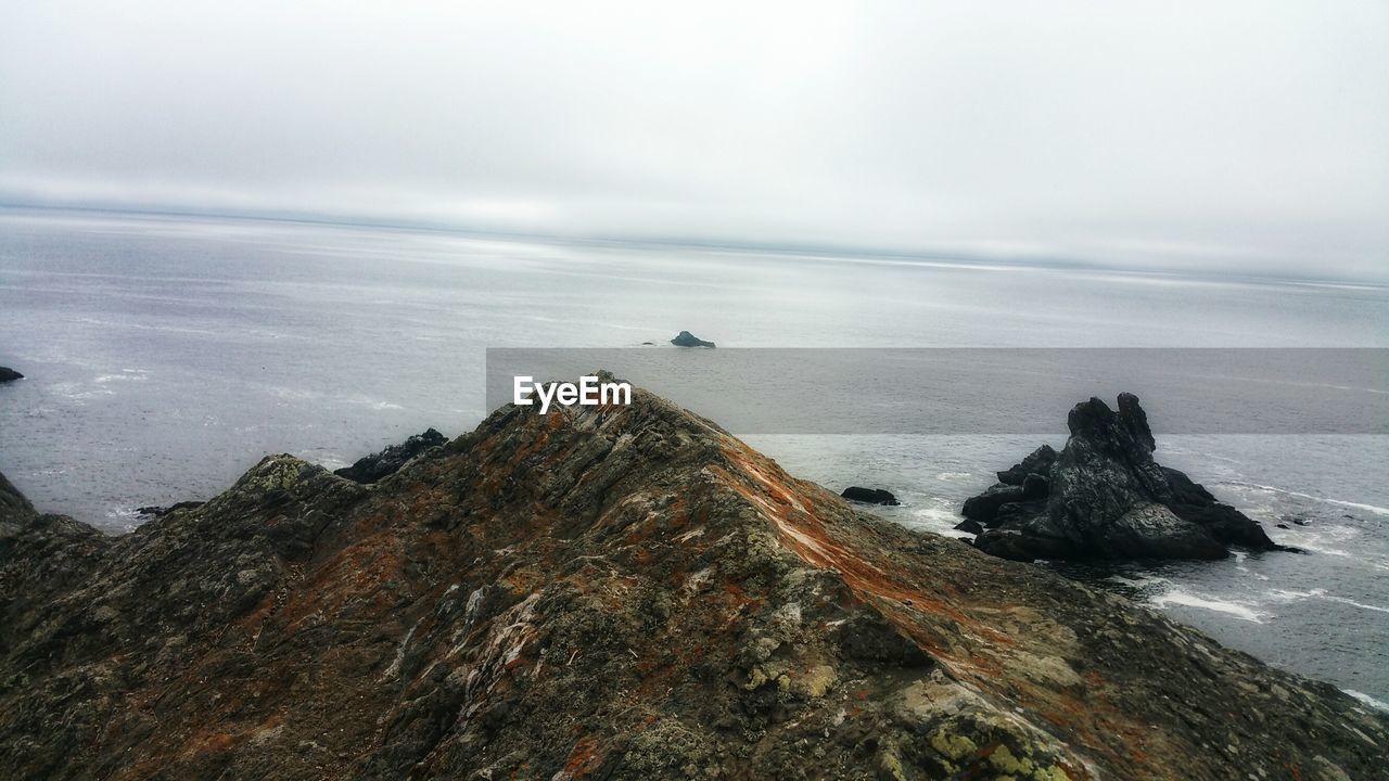 ROCK FORMATION ON SEA AGAINST SKY