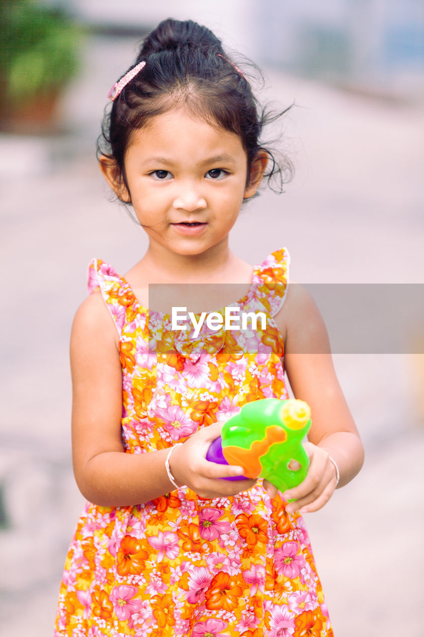 Portrait of cute girl holding toy while standing outdoors