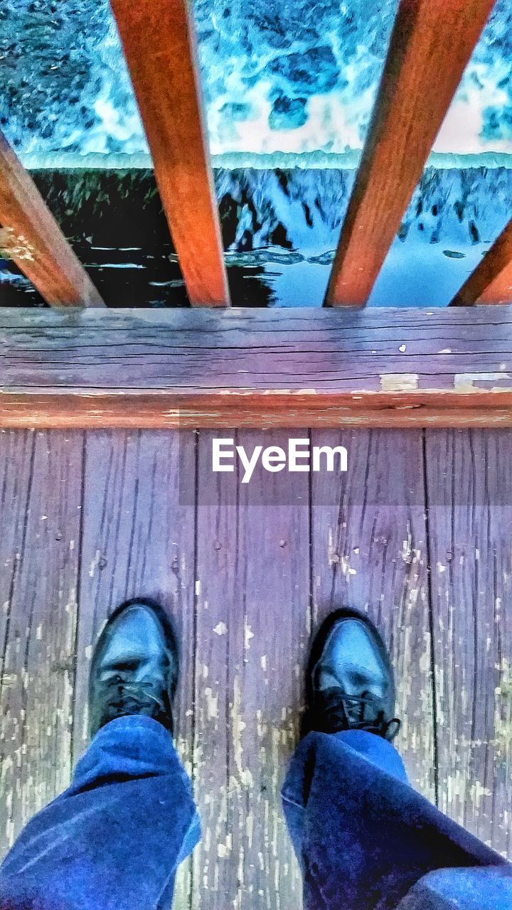 LOW SECTION OF WOMAN WALKING ON WOODEN PIER