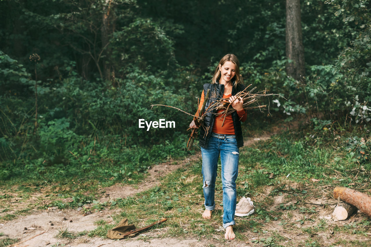 A tourist girl in nature collects firewood for a fire. a woman in close-up. the concept of travel