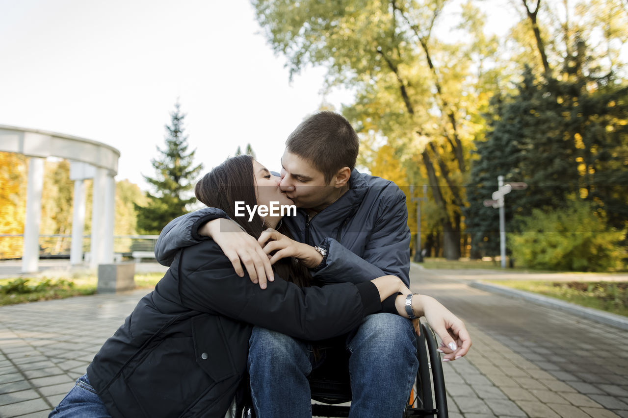Boyfriend in wheelchair kissing girlfriend in park