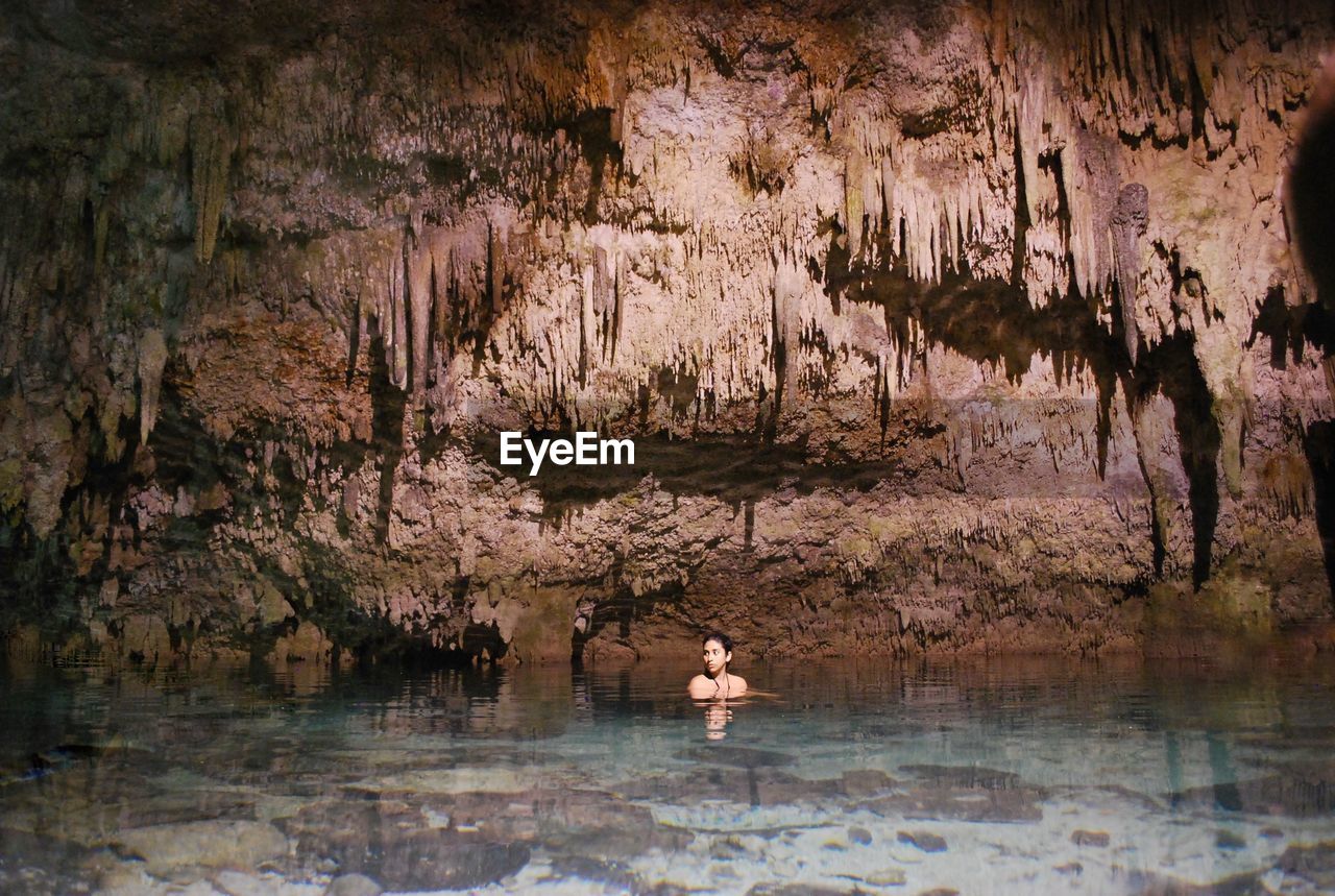 Woman swimming in pond against rock formation