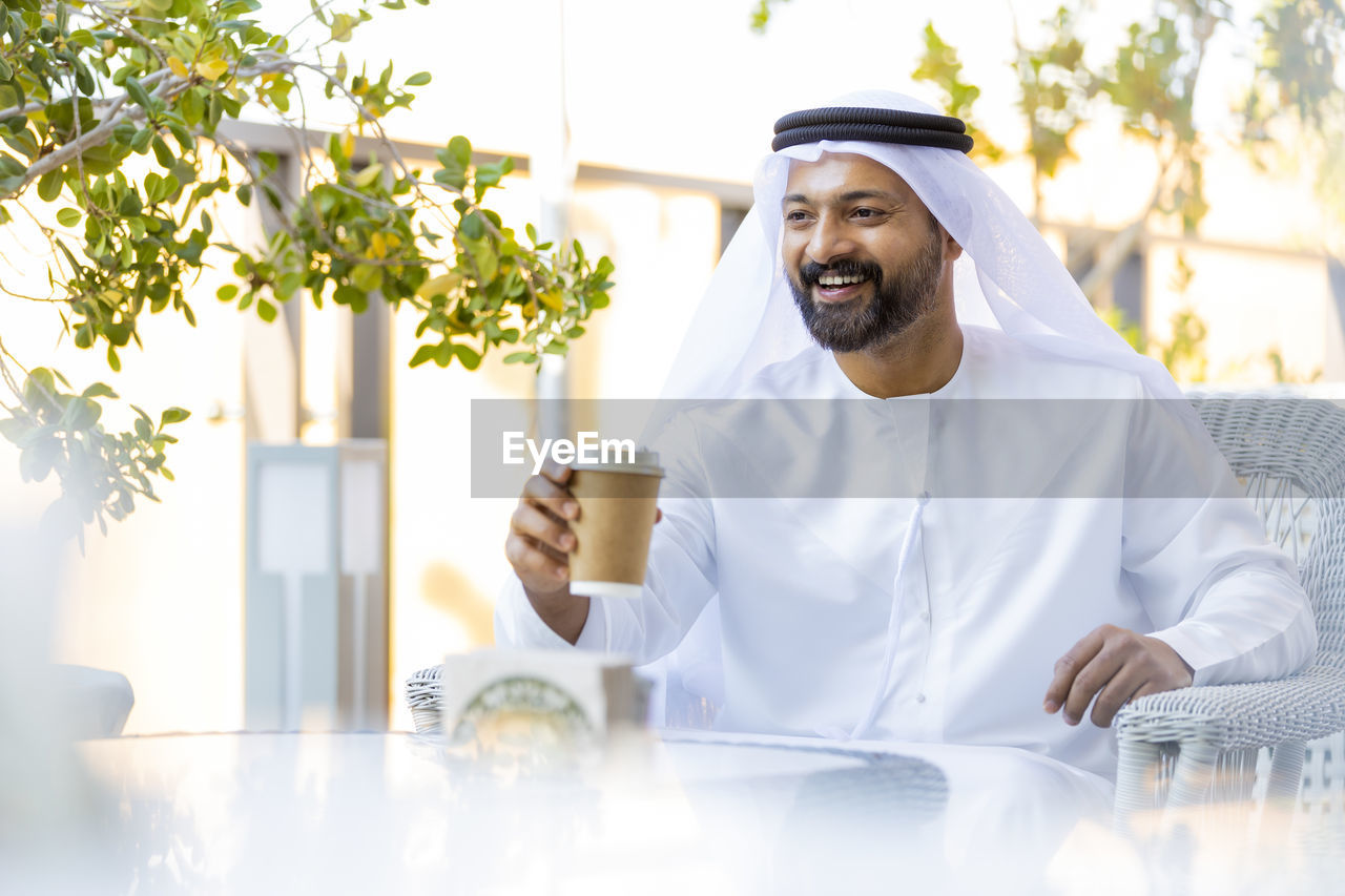Smiling man wearing traditional clothing sitting at outdoor cafe