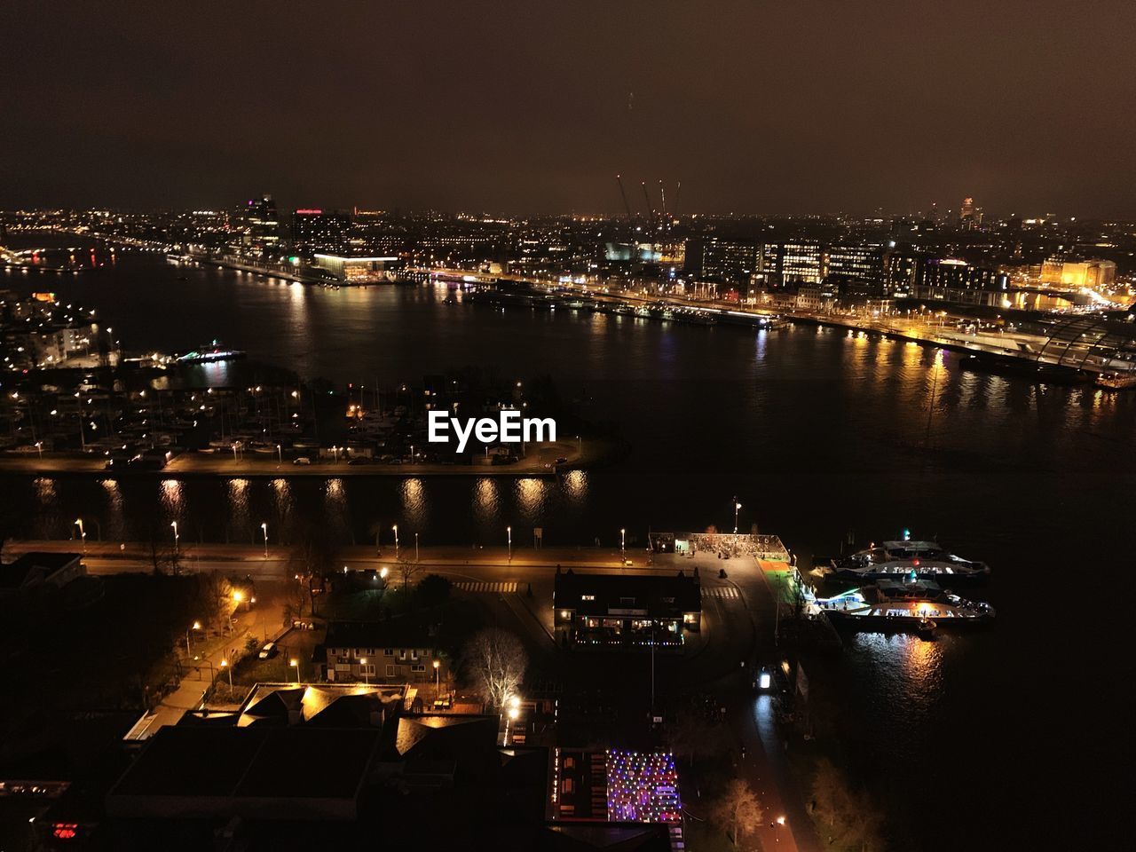 HIGH ANGLE VIEW OF ILLUMINATED BUILDINGS BY RIVER AT NIGHT