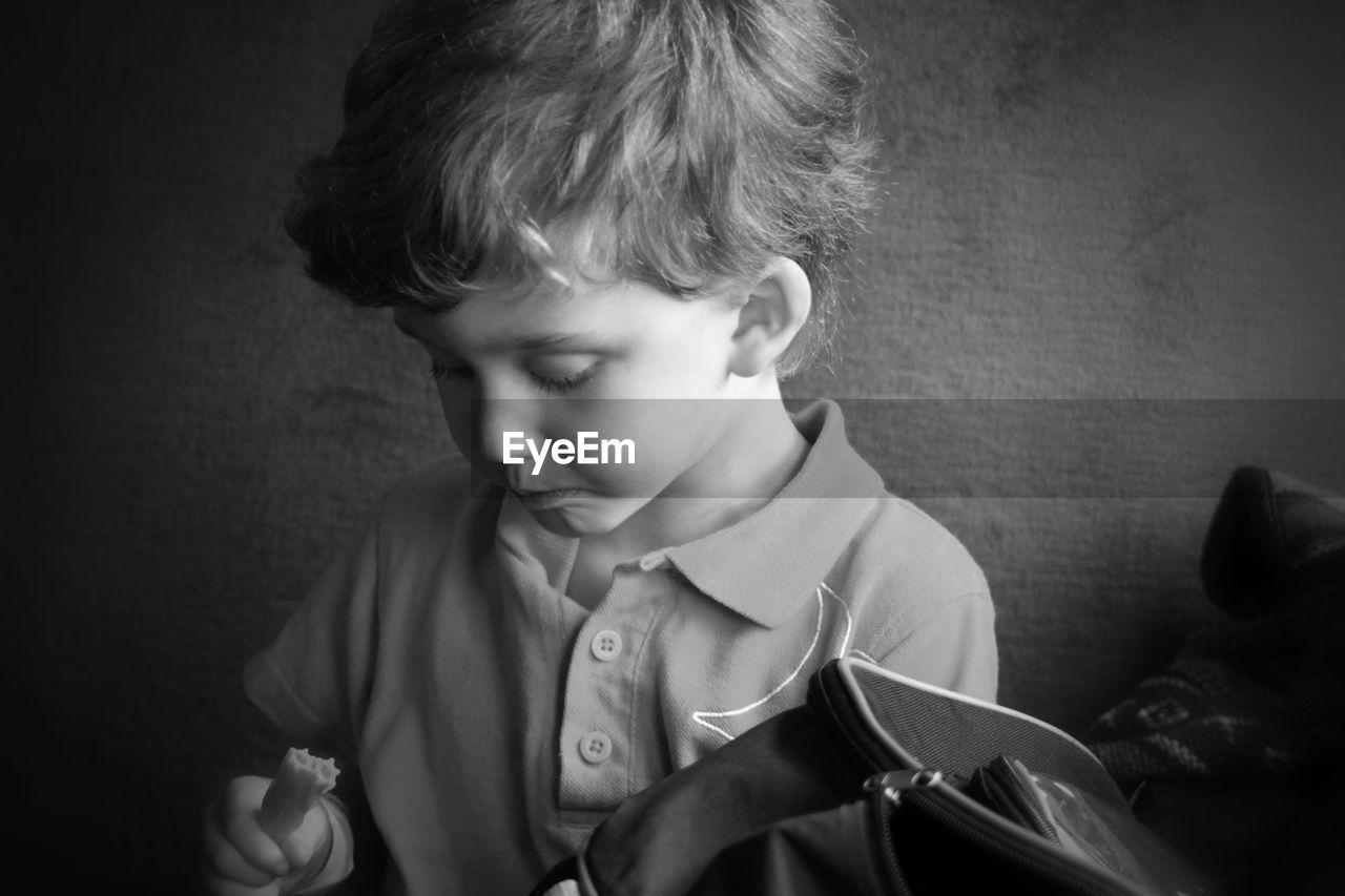 Close-up of boy holding felt tip pen while sitting against wall