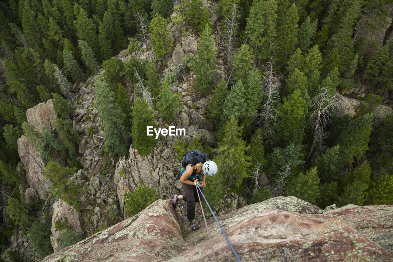 Woman rappels from summit of matron, flatirons near boulder, colorado