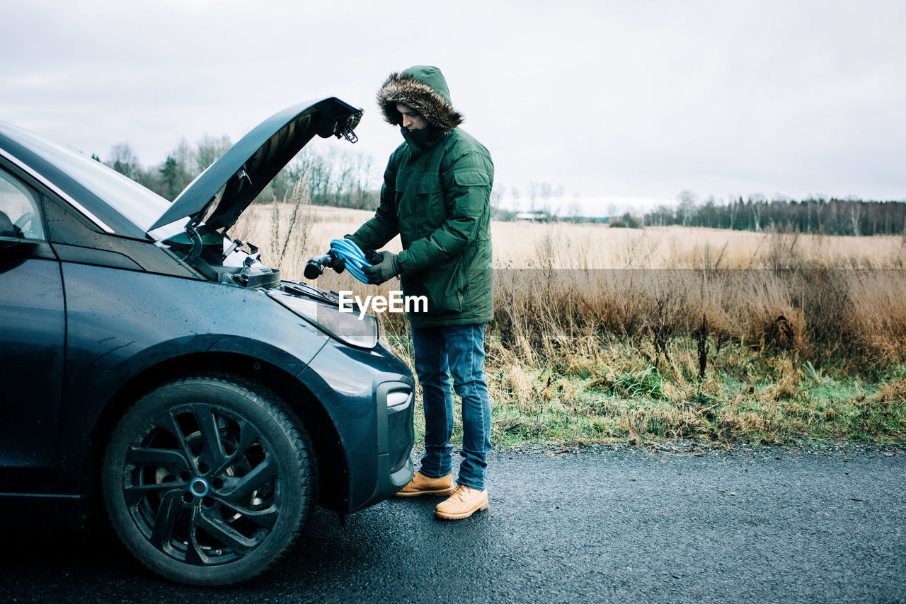 Man putting an electric car cable into the hood of the car