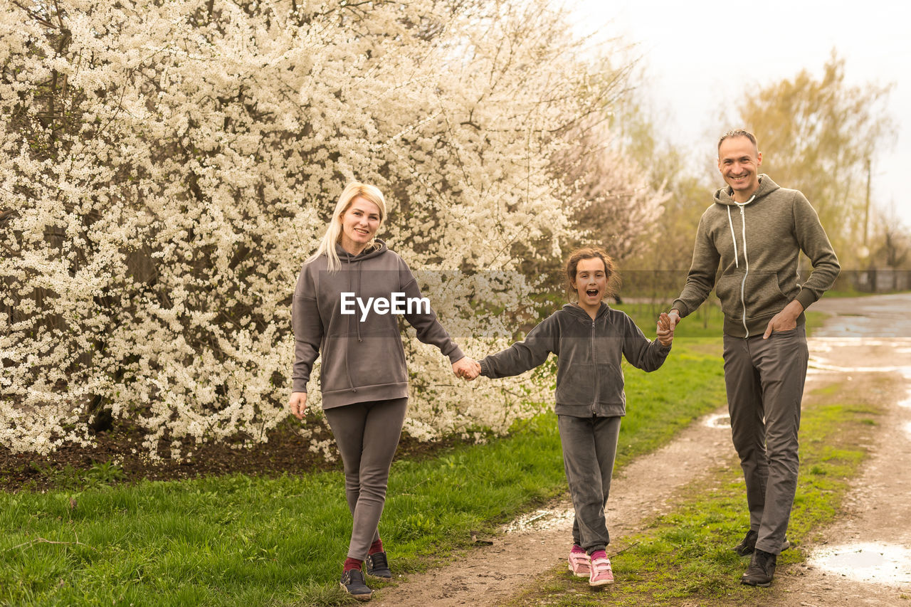 Family having fun with flowering tree in blooming spring garden