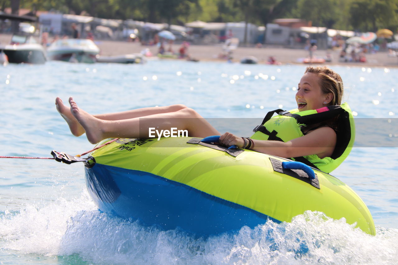 Cheerful teenage girl sitting on inflatable ring in sea