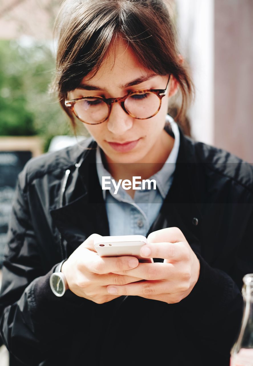 Young woman in eyeglasses using phone