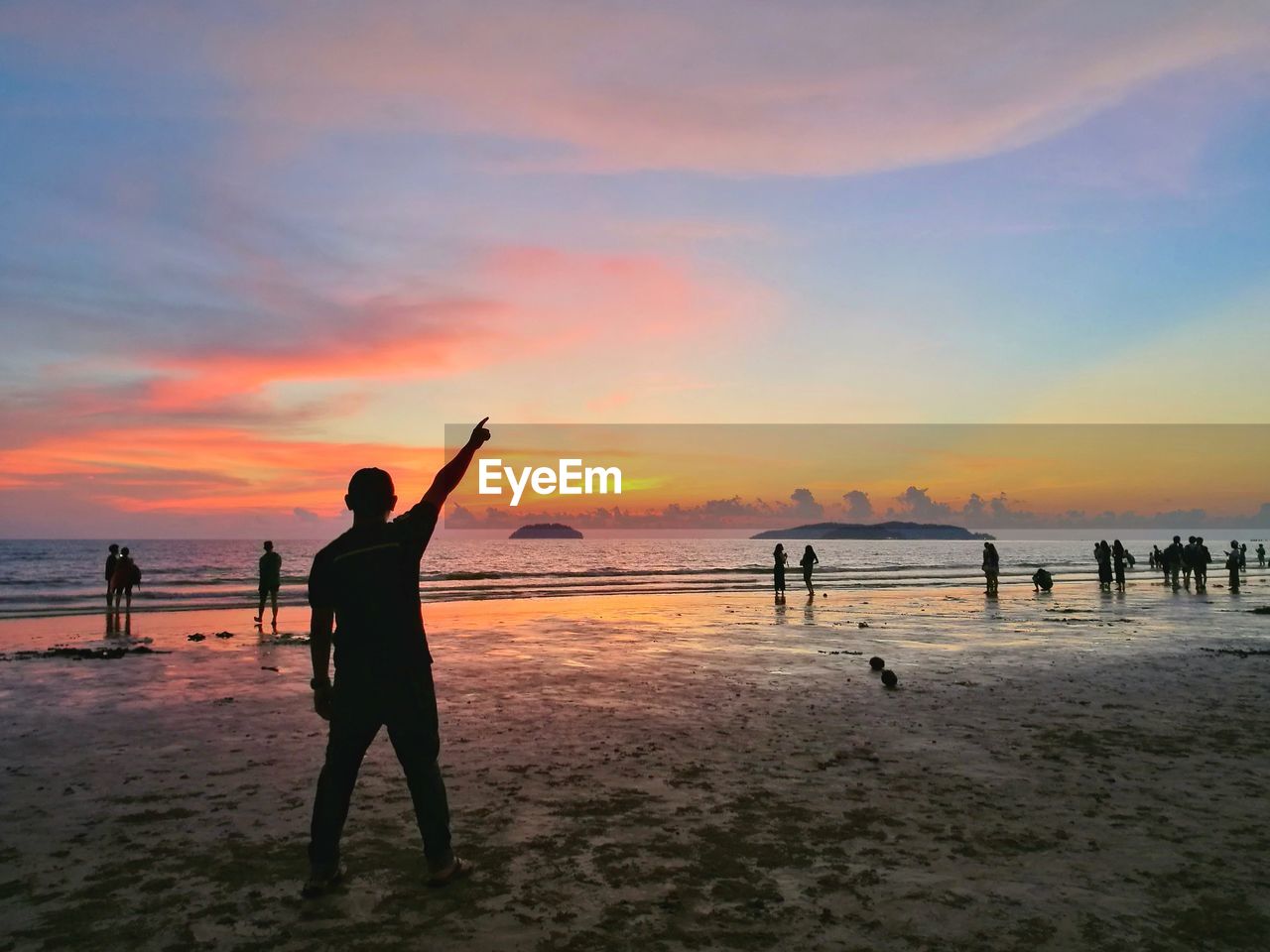 Silhouette people at beach against sky during sunset