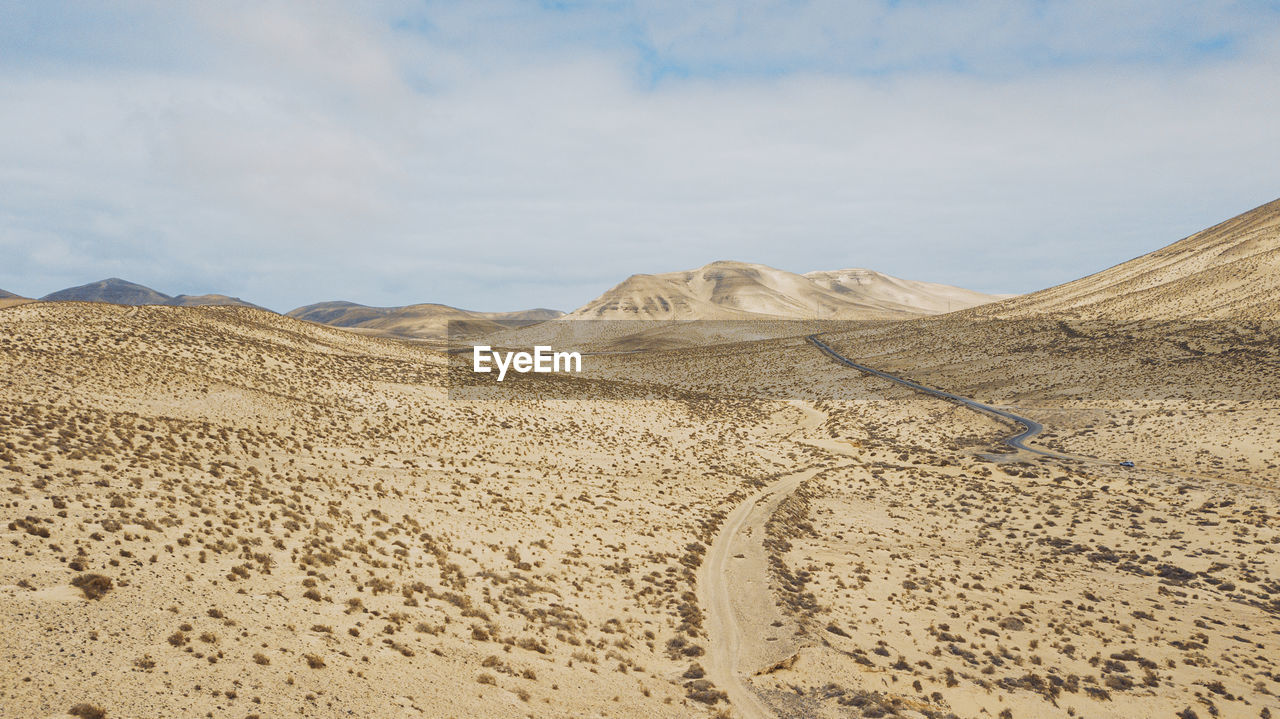 scenic view of desert against cloudy sky