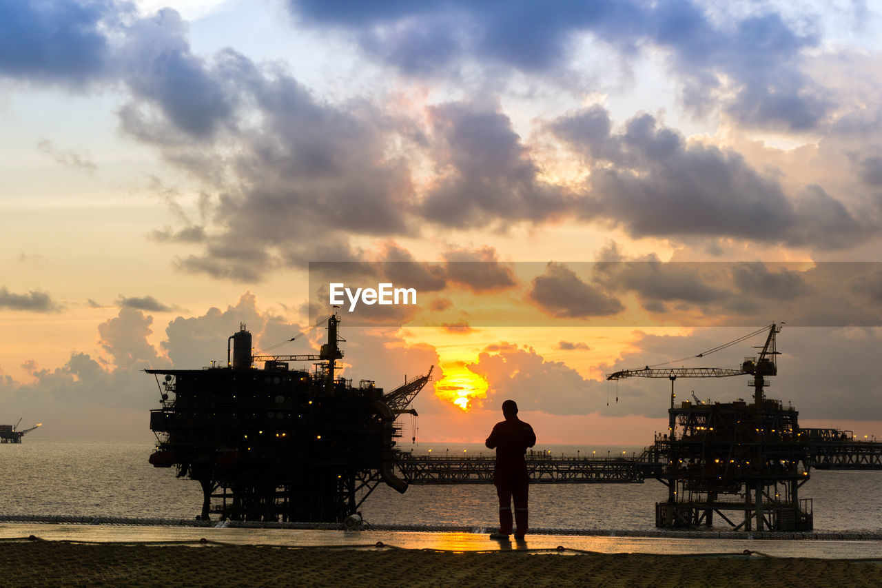 Silhouette of an offshore worker standing on a helipad of a construction work barge at offshore 