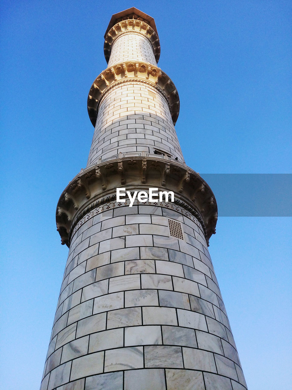 Low angle view of taj mahal minaret against clear blue sky