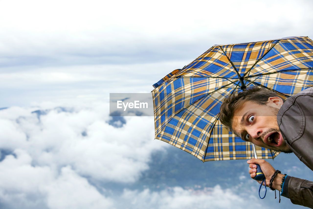 Man with mouth open against clouds