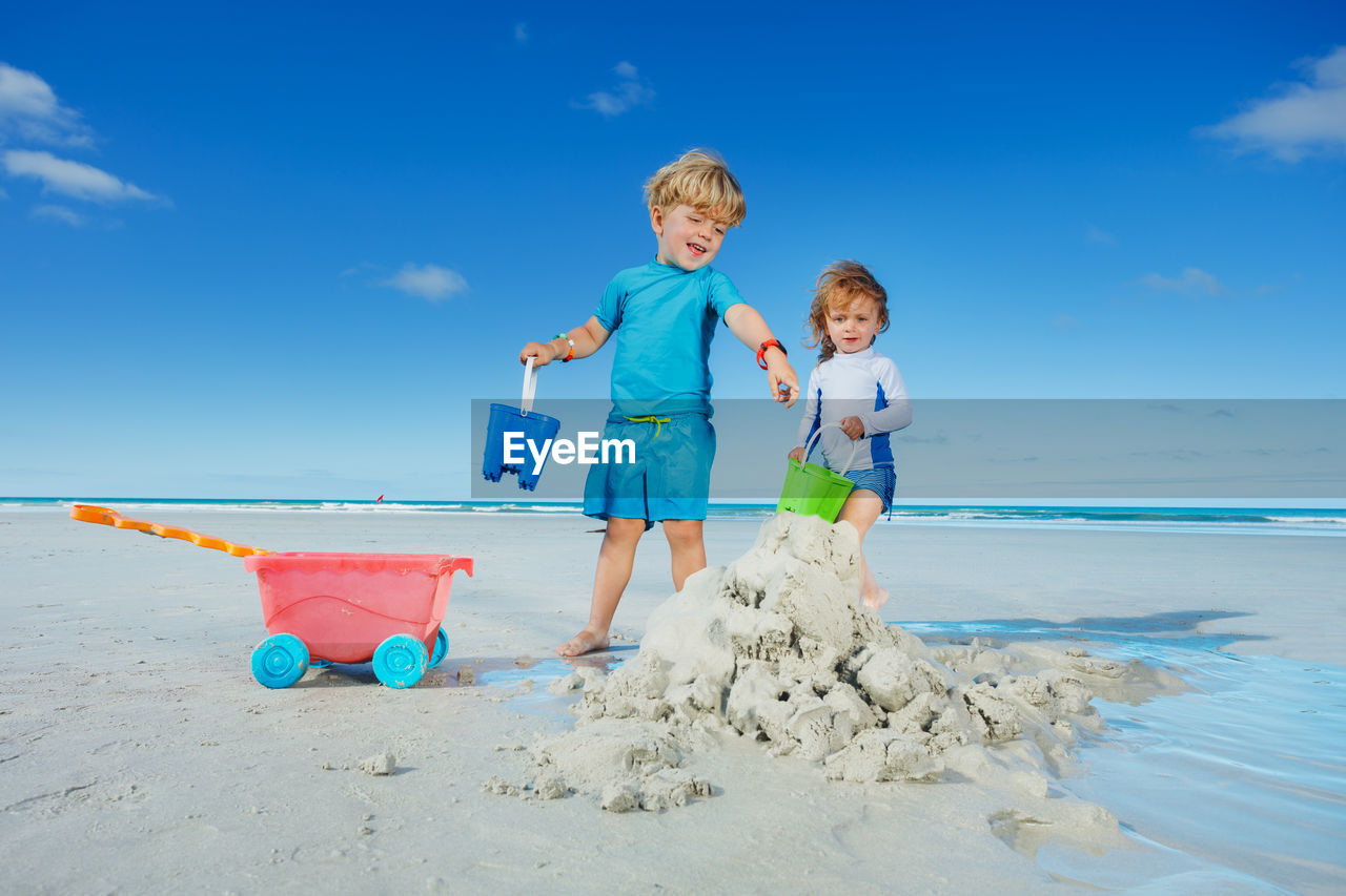 portrait of siblings playing on sand at beach