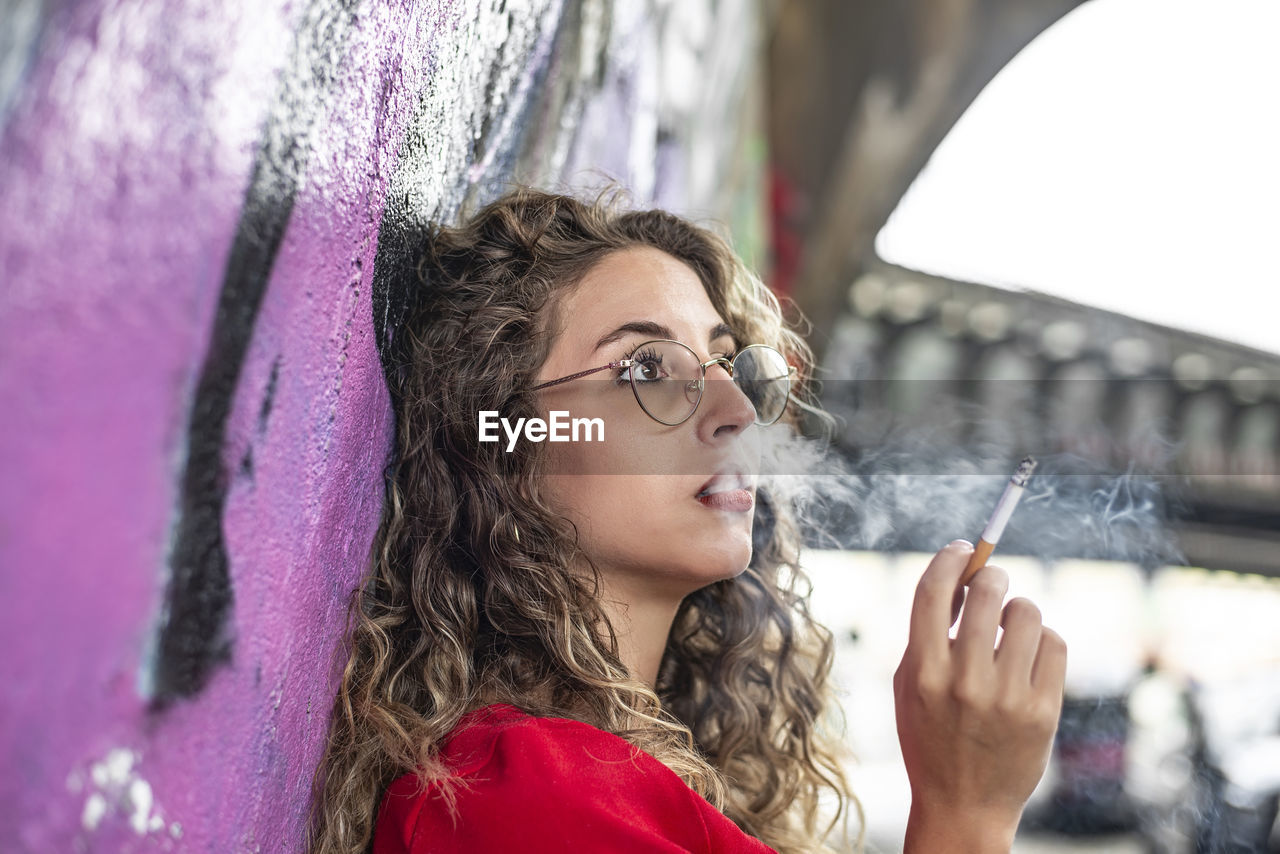 portrait of young woman standing against wall