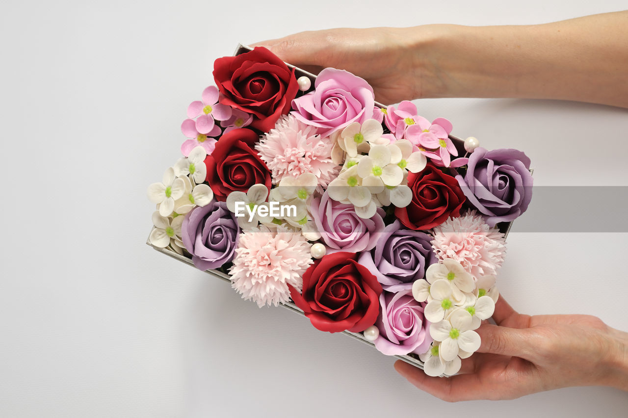 CLOSE-UP OF HAND HOLDING BOUQUET OF ROSE