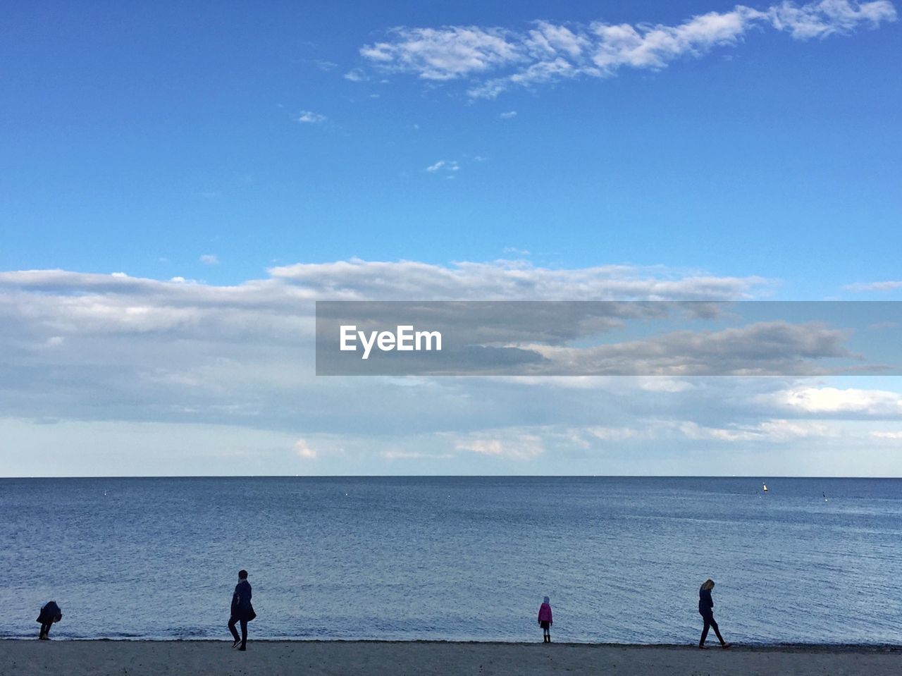 Group of people walking on calm beach