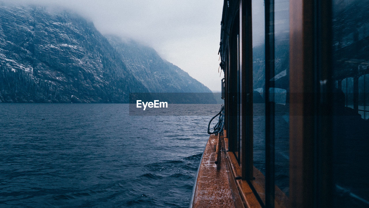 Boat sailing on sea by mountains