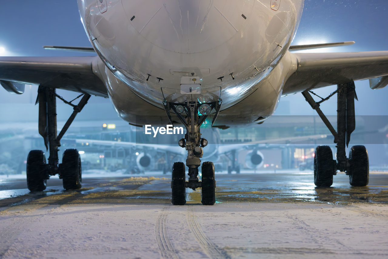 Winter frosty night at airport during snowfall. front view of airplane landing gear.