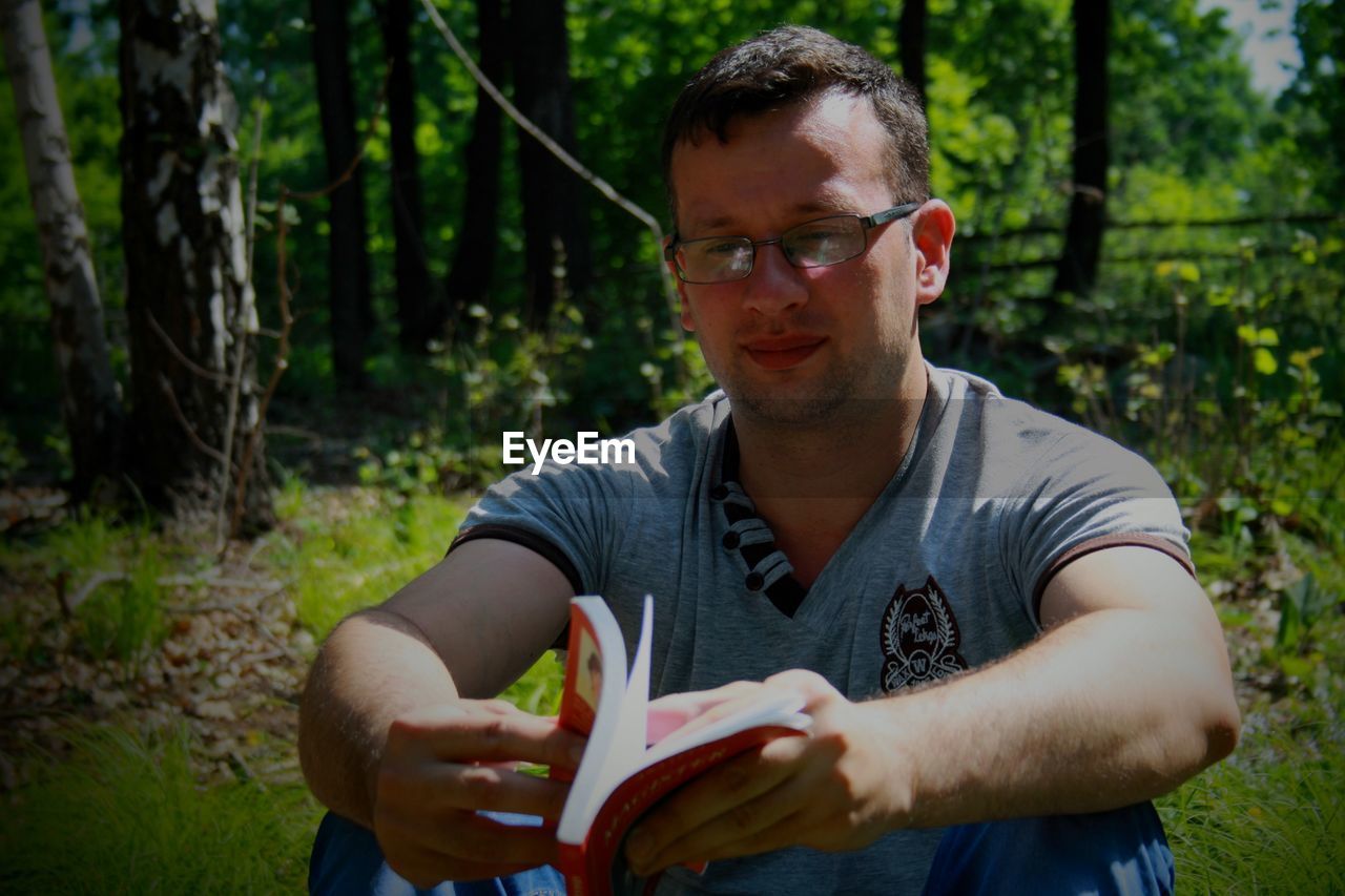 Mid adult man holding book on field