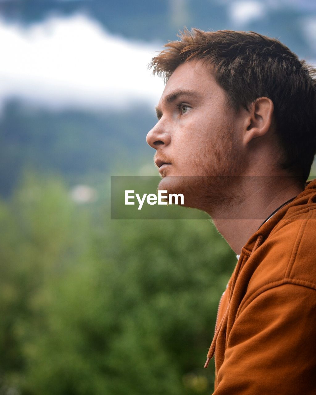 Profile view of thoughtful young man against trees