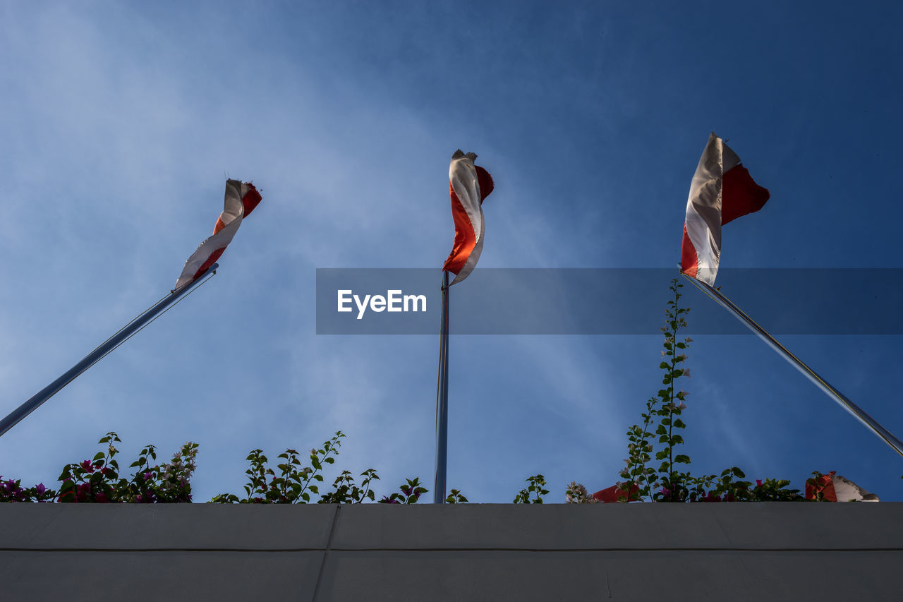 Low angle view of indonesia flags against blue sky