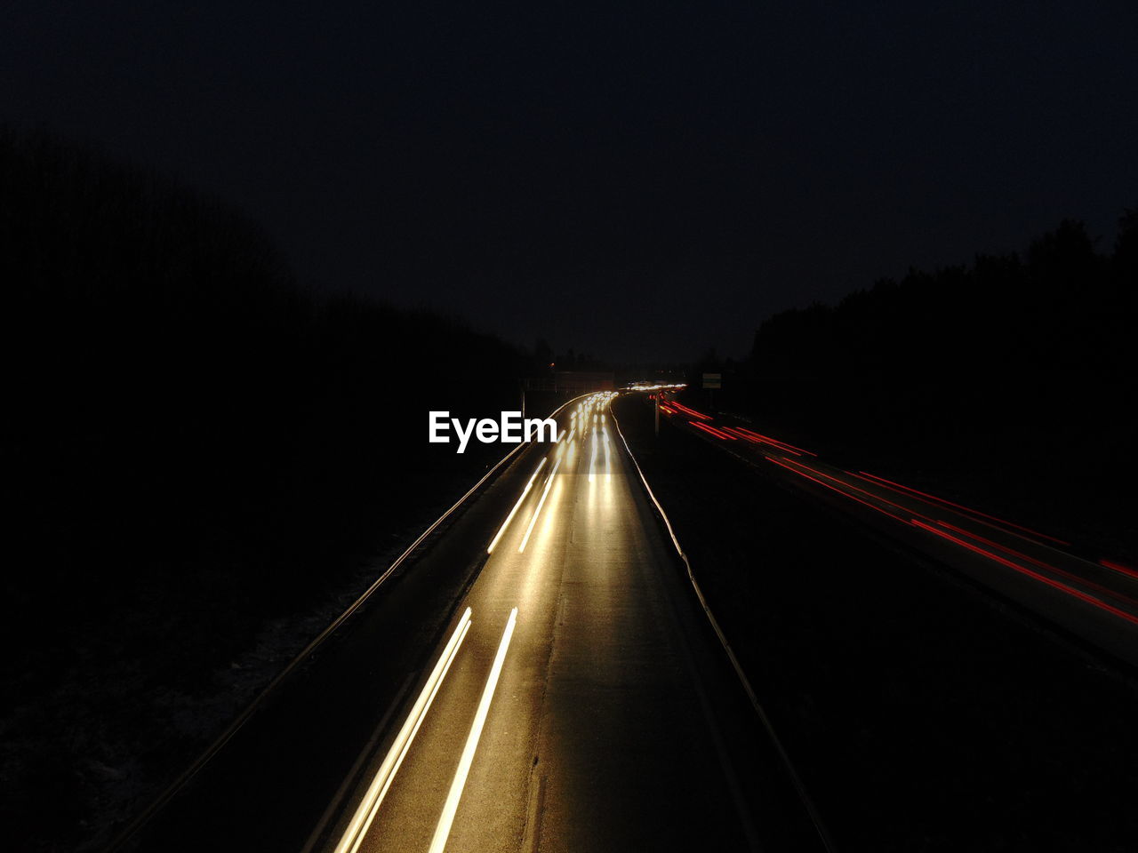 Light trails on road against sky at night