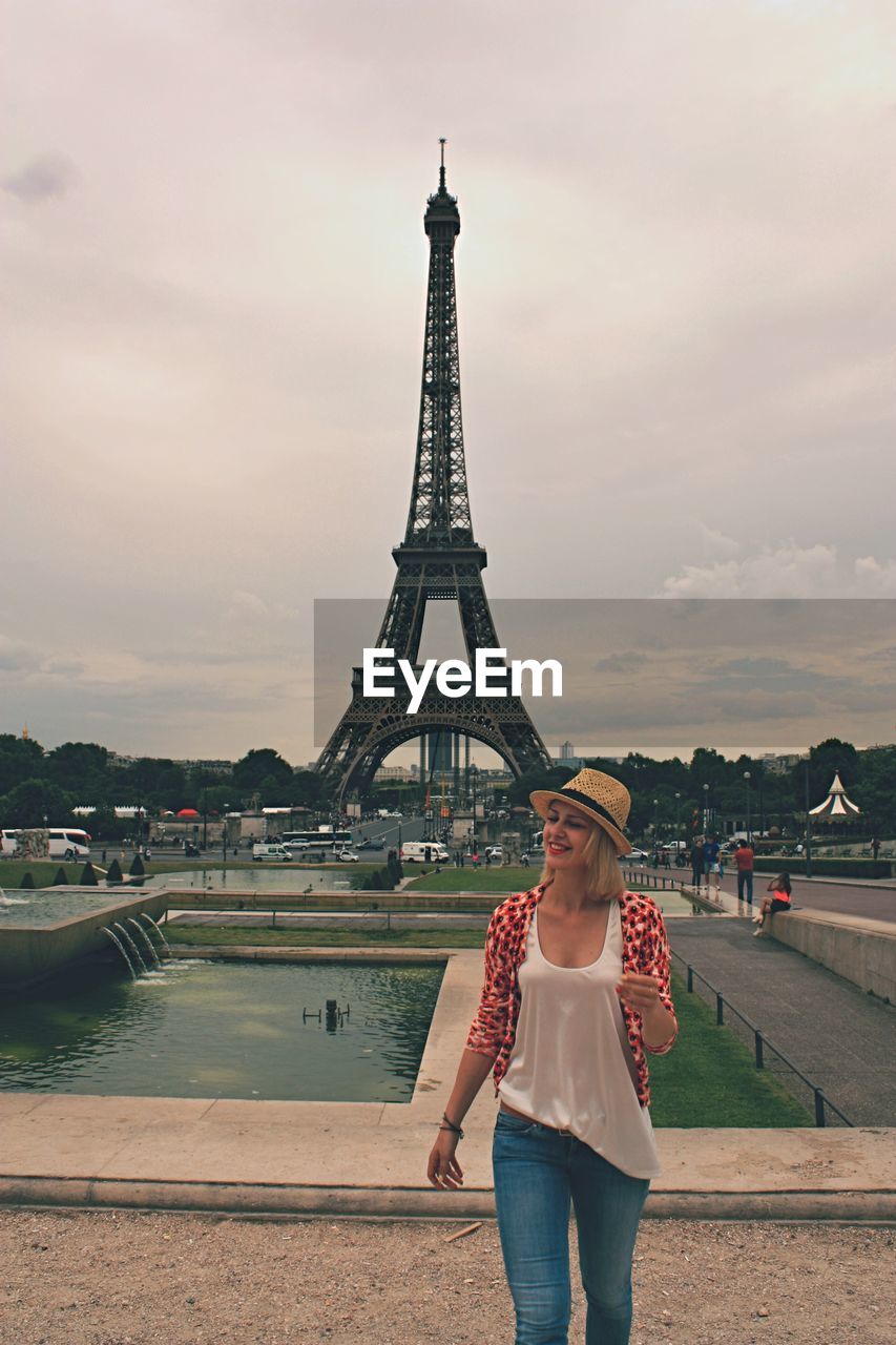 Beautiful woman standing against eiffel tower at dusk