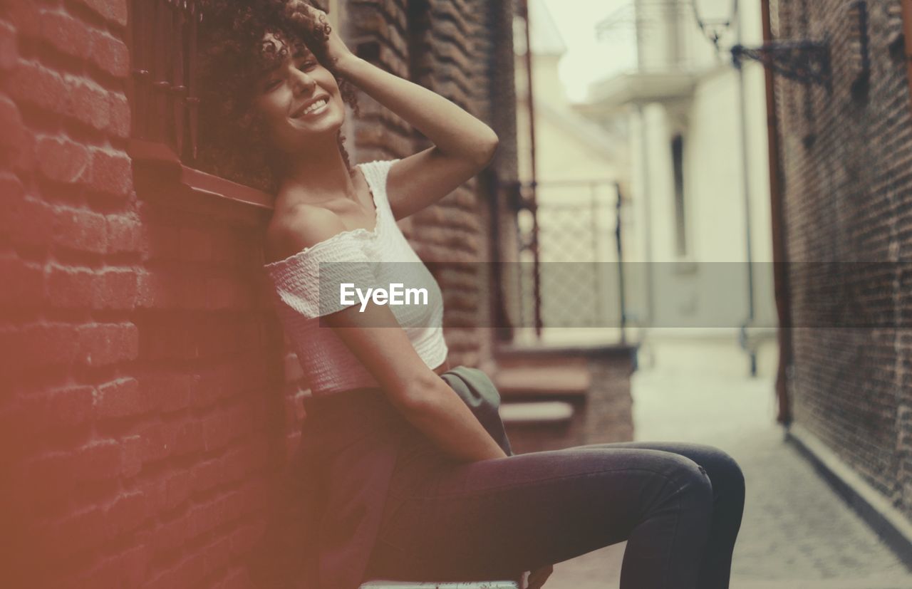 YOUNG WOMAN SITTING ON WALL