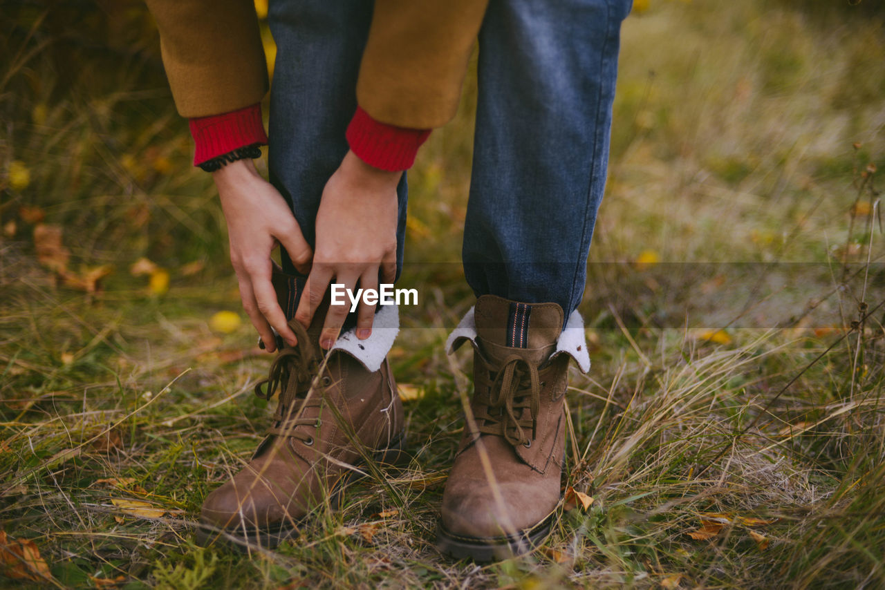 Low section of woman wearing boot on grassy field