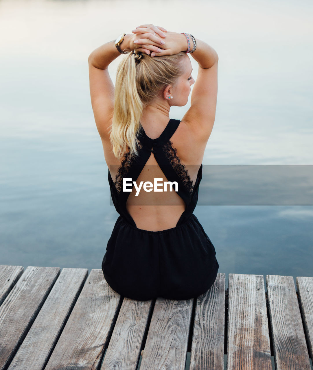 Young woman sitting on pier by lake