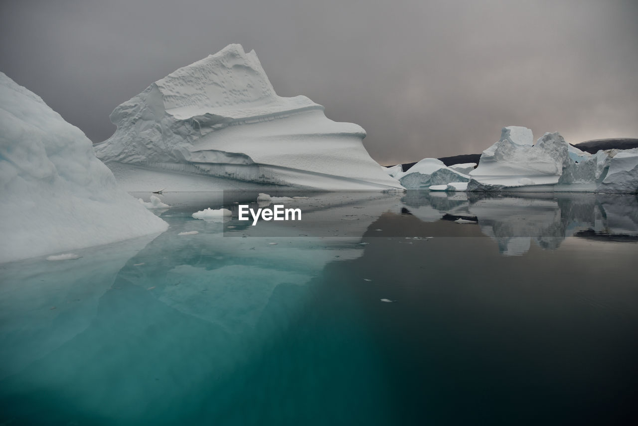 Scenic view of iceberg shapes and reflectins in mirror-like sea in greenland scoresby sound