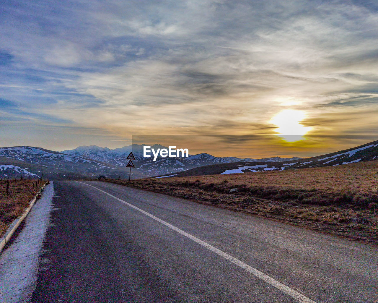 Empty road against sky during sunset