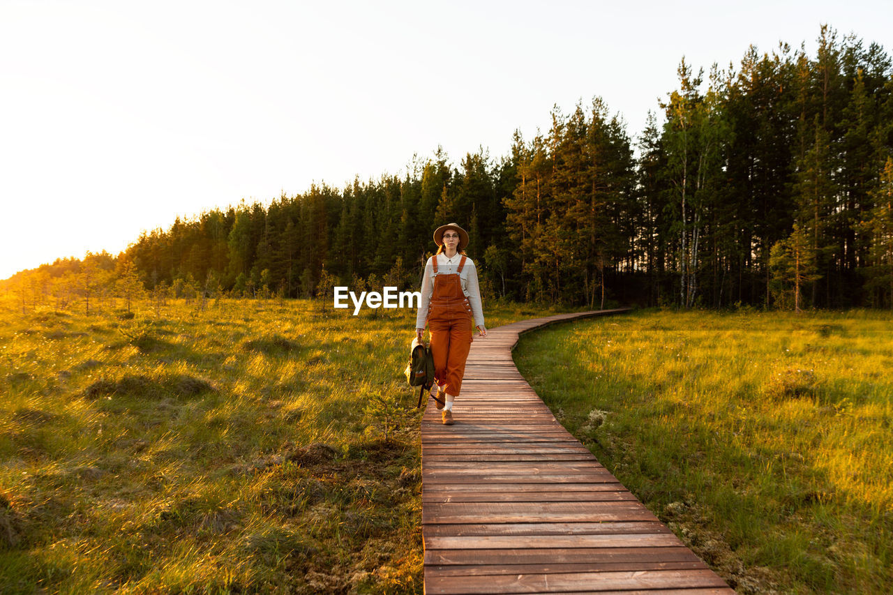 Woman botanist on ecological hiking trail. naturalist exploring wildlife ecotourism walking on path