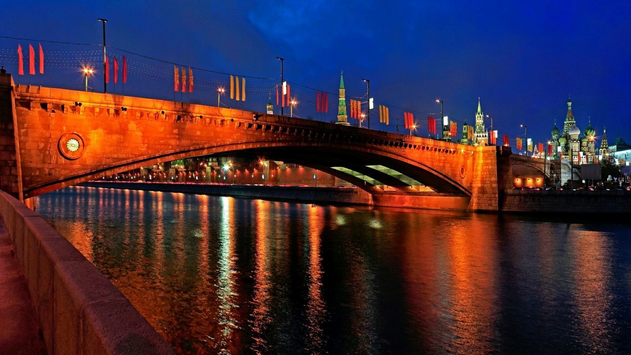 ILLUMINATED BRIDGE OVER RIVER AT NIGHT