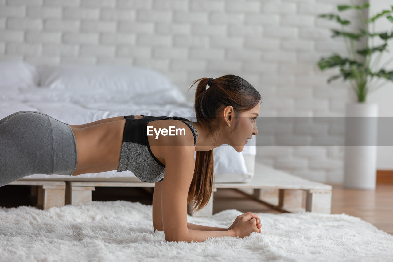 Side view of woman exercising at home