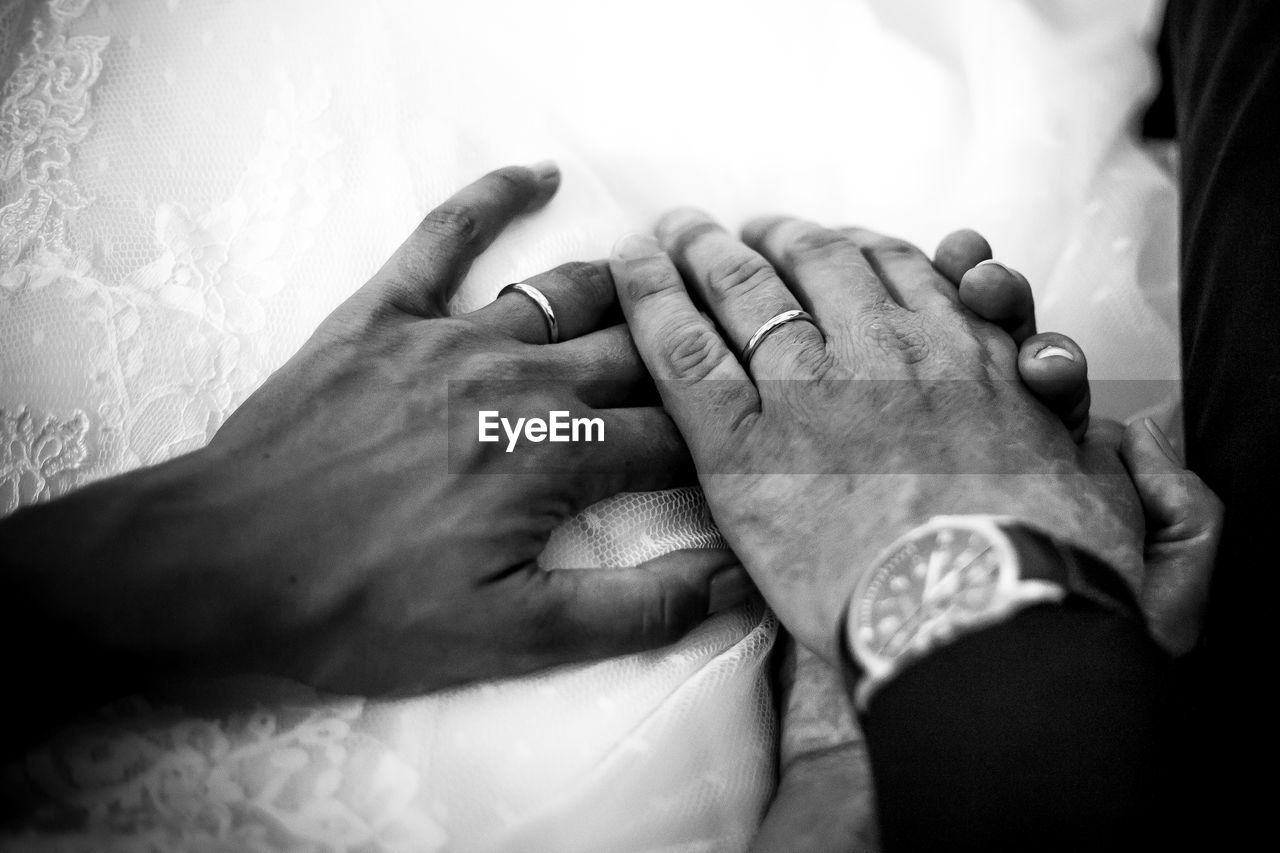 Cropped image of bride and groom holding hands