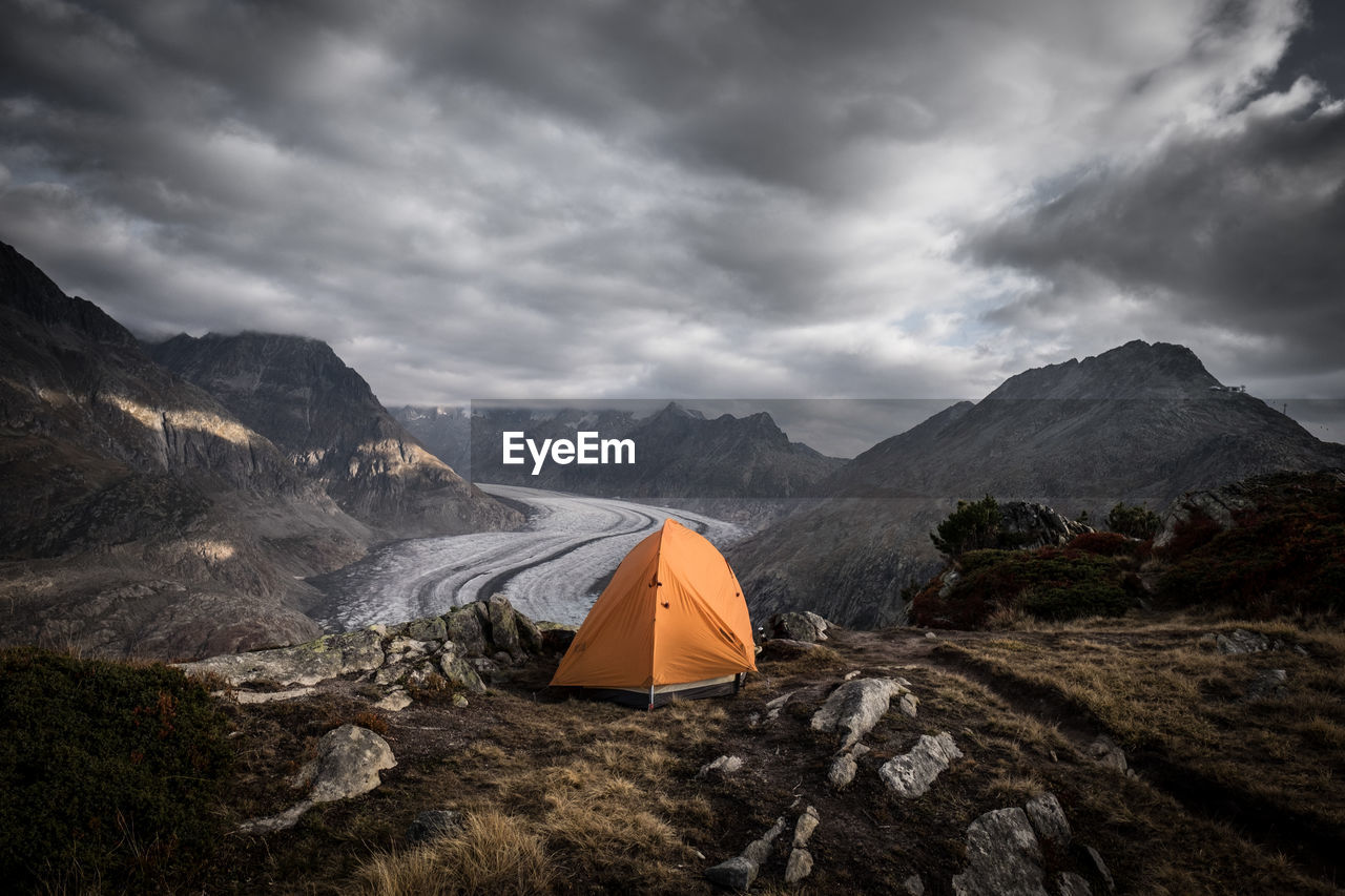 Tent on mountain against cloudy sky