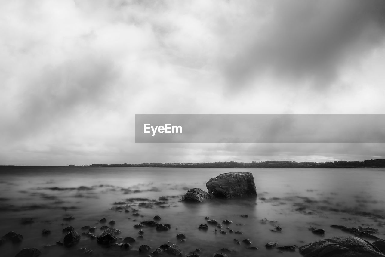 water, sky, sea, cloud, black and white, land, beach, monochrome photography, monochrome, scenics - nature, beauty in nature, horizon, nature, rock, ocean, wave, environment, tranquility, coast, horizon over water, overcast, tranquil scene, wind wave, storm, shore, dramatic sky, no people, outdoors, landscape, body of water, cloudscape, seascape, coastline, travel destinations, storm cloud, darkness, dusk, day, long exposure, sand, reflection